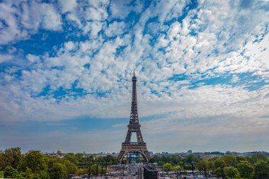 Güneşli bir günde Paris 'teki Eyfel Kulesi' nin panoramik manzarası. Arkasında bulutlar olan mavi bir gökyüzü..