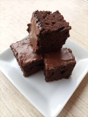 Taze ev yapımı brovniler arka planda bulanık beyaz bir tabakta dilimler.