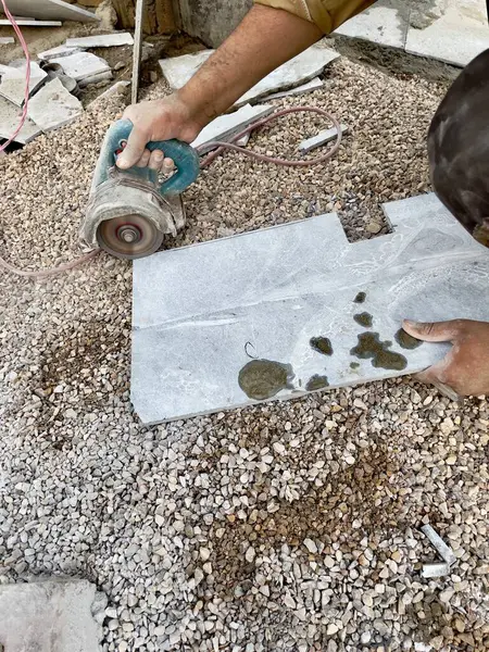 Bir inşaat işçisinin yakın plan fotoğrafı. Fayans ya da taş kesmek için el değirmeni kullanıyor.. 