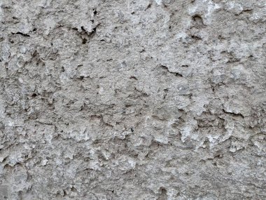 Çatlak, yıpranmış beton bir duvarın yakın plan çekimleri, arkaplan, tasarım örtüleri ve mimari referanslar için ideal alçı ve pürüzlü dokuyu gösteriyor.