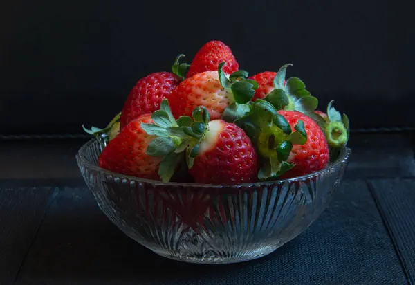 Yeşil yapraklı taze kırmızı çileklerle yapılmış şeffaf cam kavanoz.