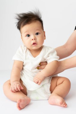 Beyaz bir yüzeyde sırt üstü yatan bir bebek. 