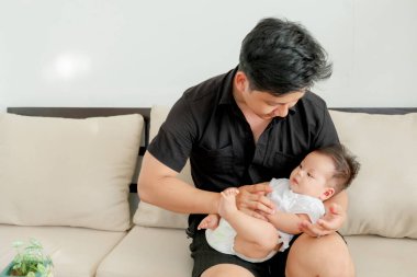 Genç baba ve Asyalı bebek birlikte oynuyorlar.