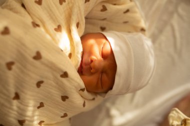 Battaniyeye sarılı bir bebek yatağın üstünde yatıyor.