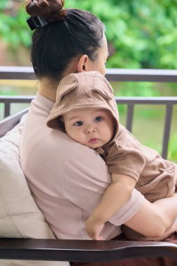 Genç Asyalı anne ve şirin bebeği bahçede oturuyor.