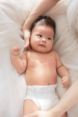 Beyaz bir battaniyenin üzerinde yatan bir bebek.