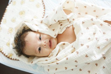 Battaniyeye sarılı yatağın üzerinde yatan bir bebek.