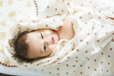 Battaniyeye sarılı yatağın üzerinde yatan bir bebek.