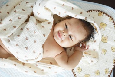 Battaniyeye sarılı yatağın üzerinde yatan bir bebek.