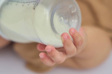 Bebeğimin eli şişeye sarılırken yakın plan.