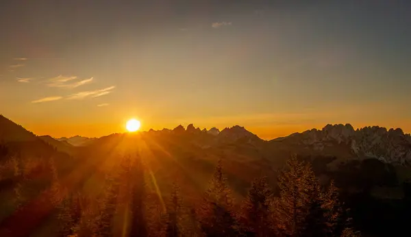 stock image The sun shining on mountains and trees during sunset