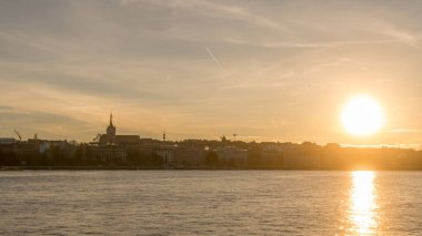 Gün batımında Cenevre şehri, bir tarafında heybetli katedrali, diğer tarafında güneş, Cenevre Gölü 'nün sularına yansıyor.