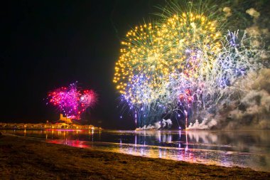 Gruissan, Aude ve Güney Fransa 'da havai fişek gösterisi. Gökyüzünde çok renkli buketler parıldıyor ve gölün suyuna yansıyor..
