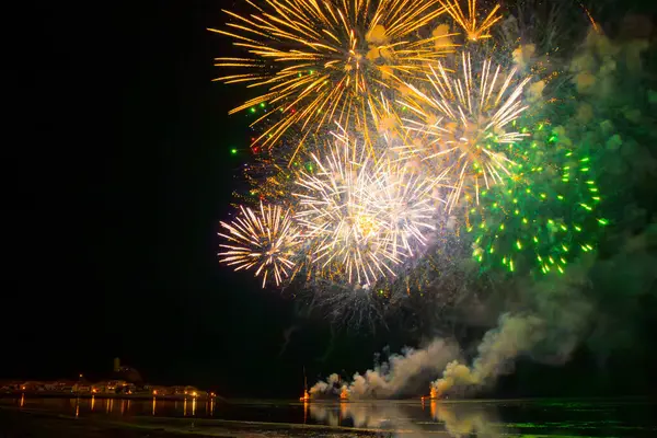 Gruissan, Aude ve Güney Fransa 'da havai fişek gösterisi. Gökyüzünde çok renkli buketler parıldıyor ve gölün suyuna yansıyor..