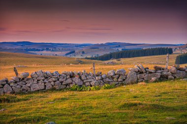 Aubrac dağlarında akşam manzarası. Fransa 'nın merkezinde taş ve kaya duvarları olan güzel bir bahar akşamı..