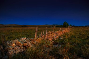 Aubrac dağlarında akşam manzarası. Fransa 'nın merkezinde taş ve kaya duvarları olan güzel bir bahar akşamı..