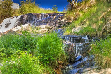 Alzeau nehrinin manzarası Saint Denis barajının altında. Yazın Fransa 'nın güneyindeki yeşilliğin ortasında bir kayanın üzerinde şelale..
