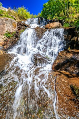 Alzeau nehrinin manzarası Saint Denis barajının altında. Yazın Fransa 'nın güneyindeki yeşilliğin ortasında bir kayanın üzerinde şelale..