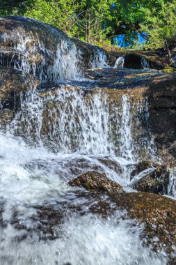 Alzeau nehrinin manzarası Saint Denis barajının altında. Yazın Fransa 'nın güneyindeki yeşilliğin ortasında bir kayanın üzerinde şelale..