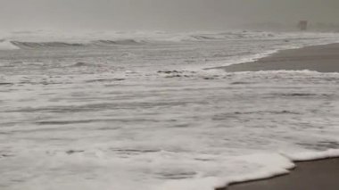 Fransa 'nın güneyindeki Port La Nouvelle sahilindeki bir fırtınanın videosu. Occitanie' nin Aude bölgesinde kötü hava koşulları sırasında dalgalar sahile çarpıyor. Bulutlu koşullarda dalgalar.