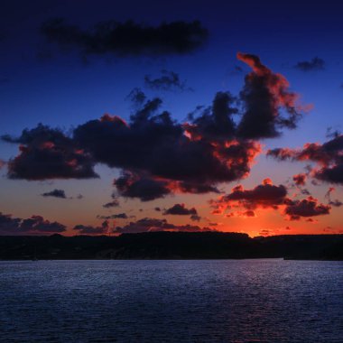 Gün batımında arka planda bitkiler ve akşam güneşi. Bulutlar gökyüzüne dağıldı. Uzaktaki tepeler.