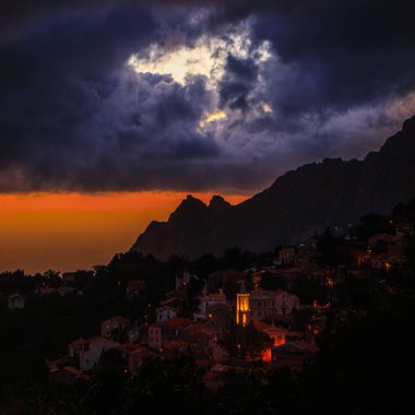 Gün batımında arka planda bitkiler ve akşam güneşi. Bulutlar gökyüzüne dağıldı. Uzaktaki tepeler.
