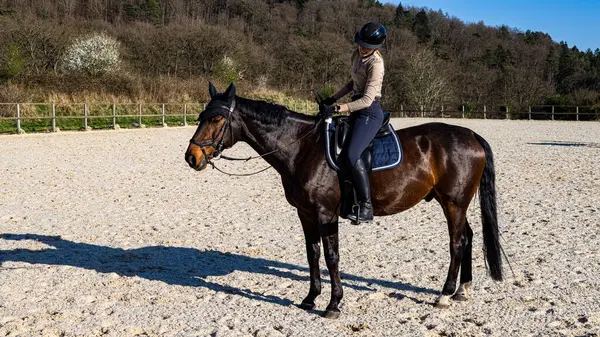 Gündüz vakti siyah atına binen genç bir kadın.