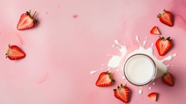 Pastel pembe arka planda izole edilmiş süt damlalarına dökülen çilekler.