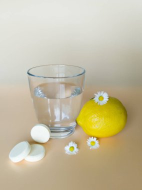 Doğal malzemelerden gelen C vitamini tablet ve limon dolu bir bardak su.