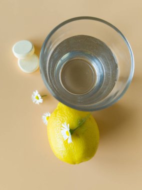 Doğal malzemelerden gelen C vitamini tablet ve limon dolu bir bardak su.