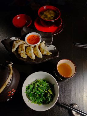 Çin yemekleri, yosun salatası, çorba, siyah arka planda acı sos.