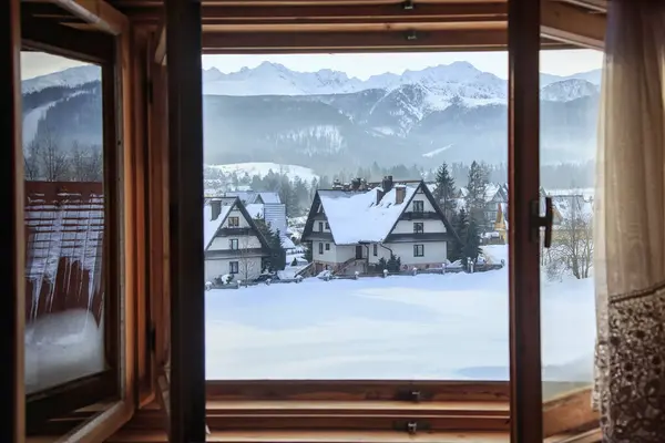 Beautiful view from an open window to a winter village with snow. Enjoying the winter weather.