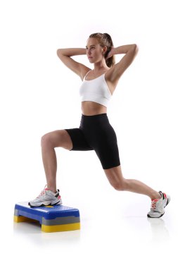 Çekici, formda bir kadın. Stüdyoda fotokopi odasıyla egzersiz yapıyor. Beyaz arka planda spor yapan sağlıklı genç bayan sporcu görüntüsü.