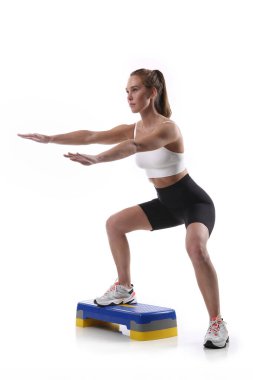 Çekici, formda bir kadın. Stüdyoda fotokopi odasıyla egzersiz yapıyor. Beyaz arka planda spor yapan sağlıklı genç bayan sporcu görüntüsü.