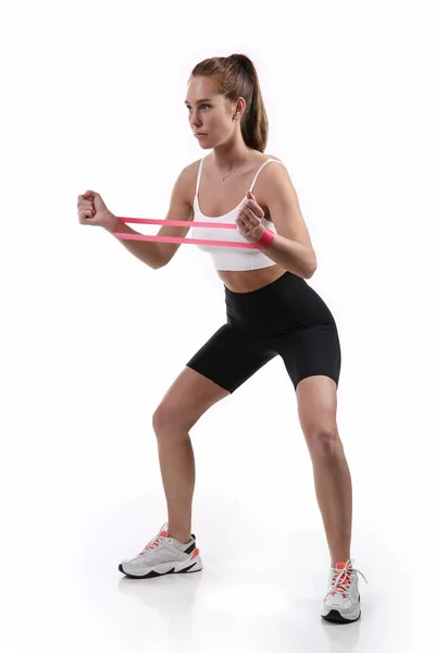 Fitness egzersizi. Beyaz arka planda izole edilmiş, direniş bandıyla spor yapan kadın.