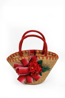 Beyaz arka planda suni çiçeklerle süslenmiş saman çocuk çantası.