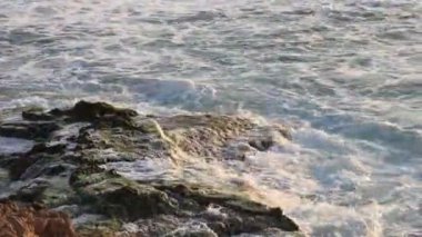 İsrail. Akdeniz kıyısı. Deniz sörfü. Kayalıklarda ve kayalıklarda dalgalar kırılıyor.