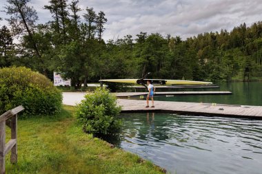 BLED, SLOVENIA - Haziran 04, 2024: Slovenya 'da Bled Gölü' nde kürek eğitimi. Bir kürekçi teknesini rıhtıma taşıyor..