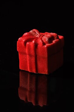 mousse cakes shaped like gift boxes, featuring a velvety red coating and shimmering gold glitter, presented on a glossy black surface clipart