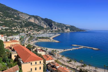 Menton 'un göz kamaştırıcı panoramik manzarası. Gök mavisi Akdeniz, kumlu plajlar, canlı bir marina ve açık mavi gökyüzünün altındaki yemyeşil tepeler. Cote d Azur, Fransa