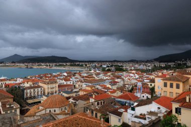 Nafplio Eski Kasabası 'nın panoramik manzarası. Terracotta çatıları ve limanı, dağların üzerinde dramatik fırtına bulutları tarafından çerçevelenmiş. Moreloponez, Yunanistan.