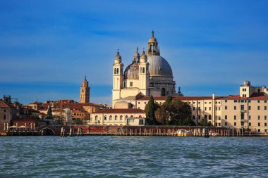 İtalya, Venedik 'teki Santa Maria della Salute Bazilikası' nın ikonik manzarası, açık mavi gökyüzü ile güneşli bir günde Büyük Kanal 'ın diğer tarafından görülüyor..