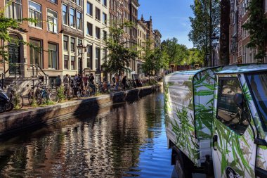 AMSTERDAM, NETHERLANDS - 31 Ağustos 2022: Amsterdam 'da bisiklet, tarihi evler ve kenevir temalı Hash Marihuana & Hemp Müzesi yakınlarındaki bir kanalın renkli görüntüsü.