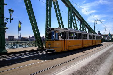 Budapeşte, Macaristan - 9 Eylül 2021: Budapeşte, Macaristan 'daki Liberty Köprüsü' nden geçen ikonik sarı tramvay. Macar başkentinin göbeğinde şehir merkezi ve şehir taşımacılığı.