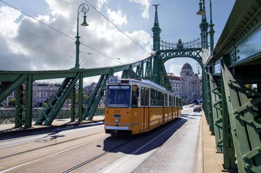 Budapeşte, Macaristan - 9 Eylül 2021: Budapeşte, Macaristan 'daki Liberty Köprüsü' nden geçen ikonik sarı tramvay. Macar başkentinin göbeğinde şehir merkezi ve şehir taşımacılığı.