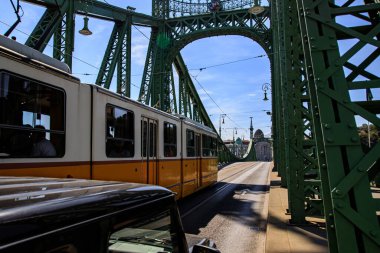 Macaristan 'ın Budapeşte kentindeki tarihi Özgürlük Köprüsü' nden klasik bir sarı tramvay geçiyor.. 