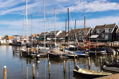 Marken, NETHERLANDS - 05 Eylül 2022: Marken, Hollanda 'daki manzaralı liman, güneşli bir günde geleneksel ahşap evler, demirlemiş tekneler ve büyüleyici bir deniz atmosferi.