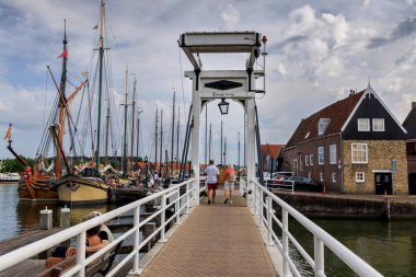 Monnickendam, NETHERLANDS - 05 Eylül 2022: Geleneksel Hollanda mimarisi ve demirlemiş yelkenli gemilerle çevrili, Hollanda 'nın Monnickendam kentindeki tarihi bir limanın üzerindeki büyüleyici yaya köprüsü.