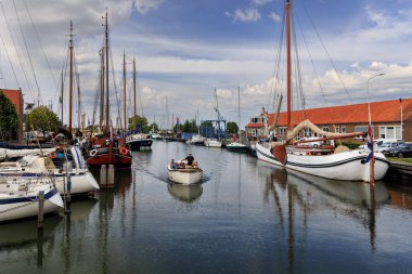 Monnickendam, NETHERLANDS - 05 Eylül 2022: Hollanda, Monnickendam 'da huzurlu liman manzarası, yelkenli tekneleri, küçük bir motorlu tekne ve kanal boyunca tarihi mimari.