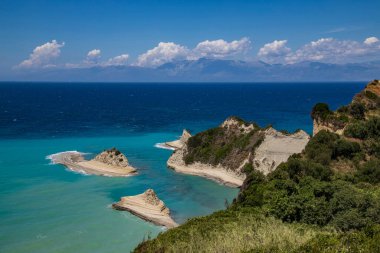 Yunanistan 'ın Corfu Adası' ndaki Drastis Burnu 'nun nefes kesici kıyı manzarası, turkuaz sular, dramatik uçurumlar ve yemyeşil Akdeniz yeşillikleri yer alıyor..